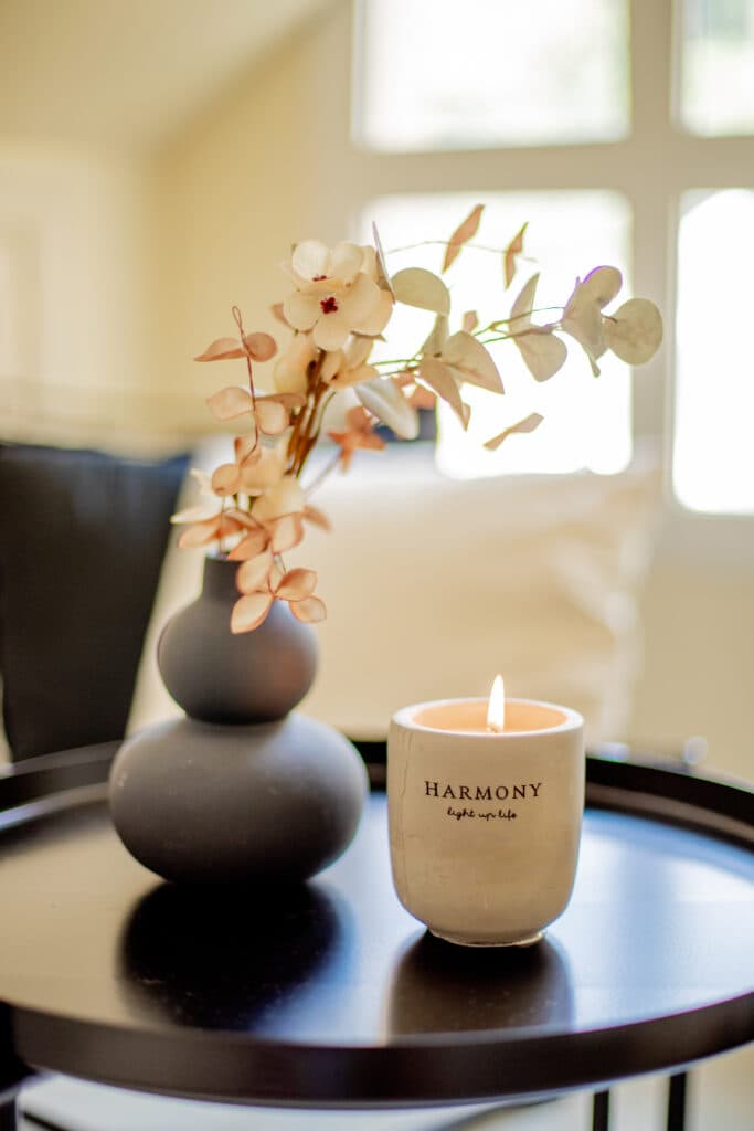 A lit candle and dried flowers on a low table in soft afternoon light