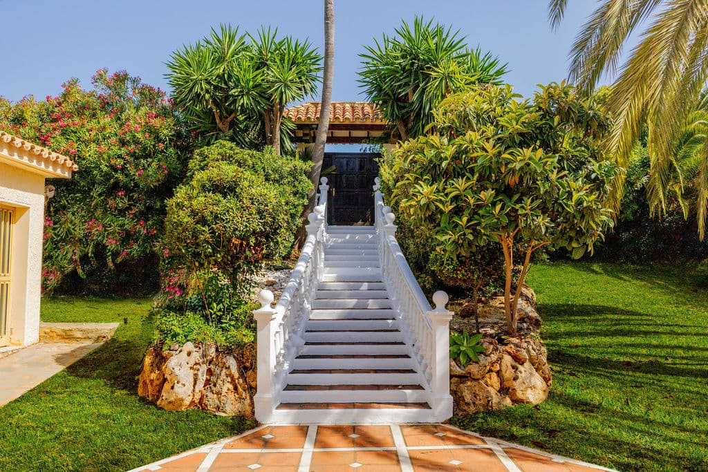 White stone steps rising through a garden of palms and bougainvillea to the villa entrance